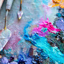 pallet knives lying next to colorful dabs of paint